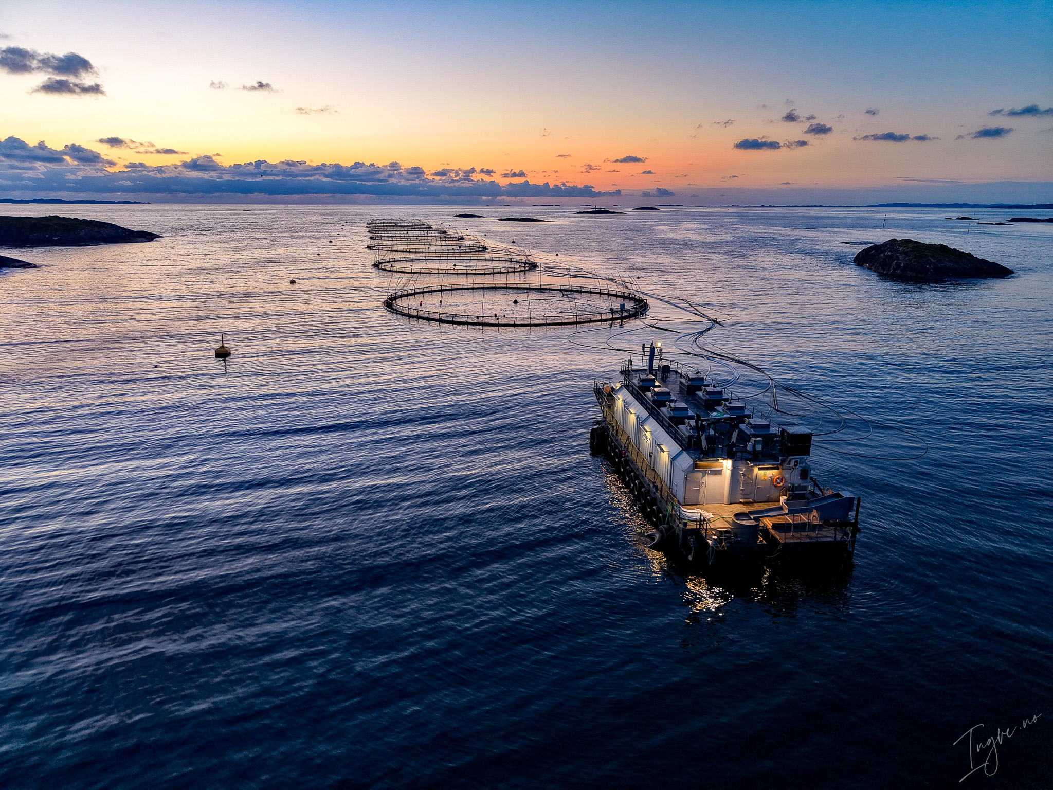 Norwegian Salmon Farm with Sea Cages and Service Vessel at Sunse